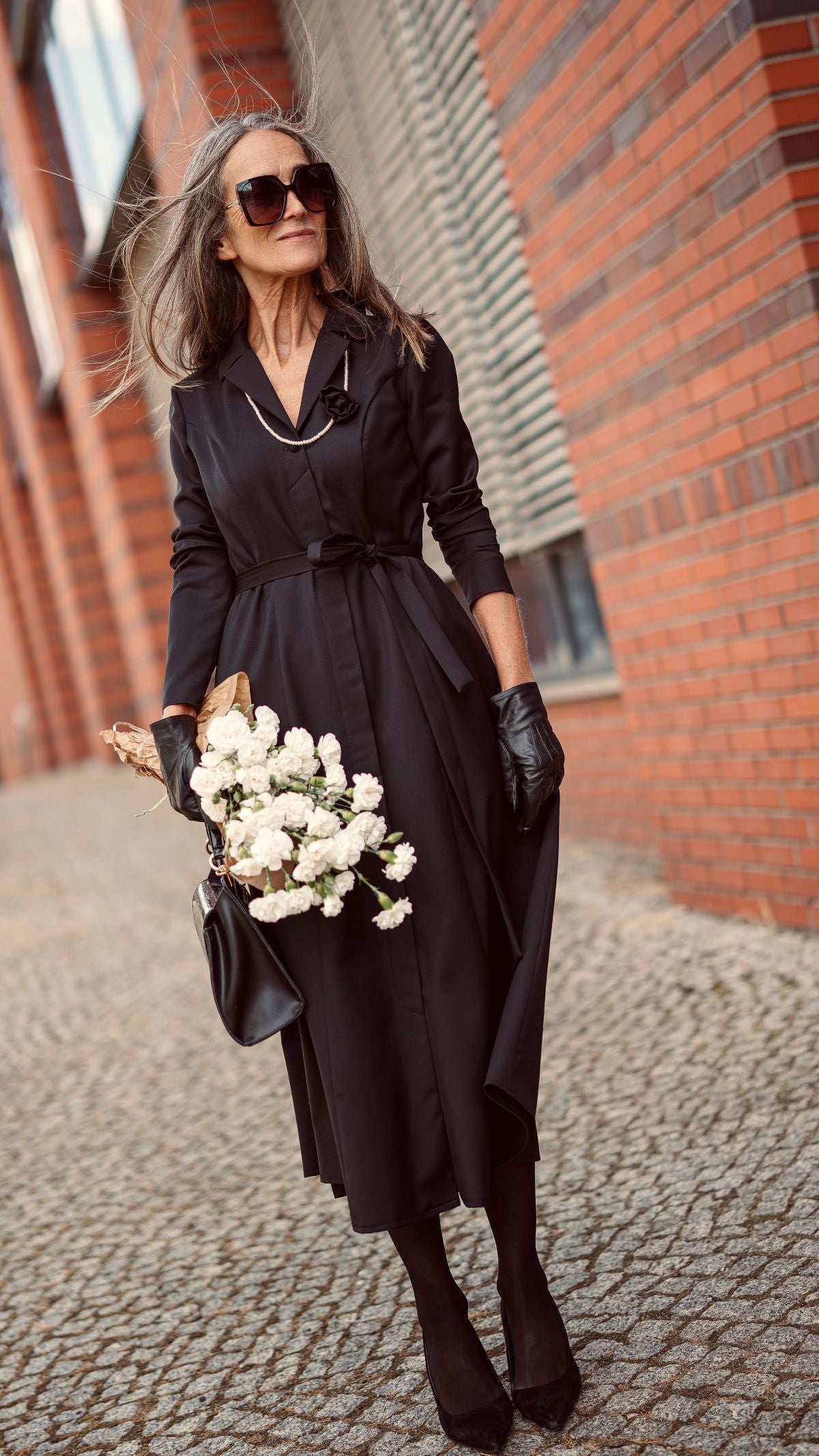 Modelka w czarnej wełnianej sukience rozpinanej idzie do pracy