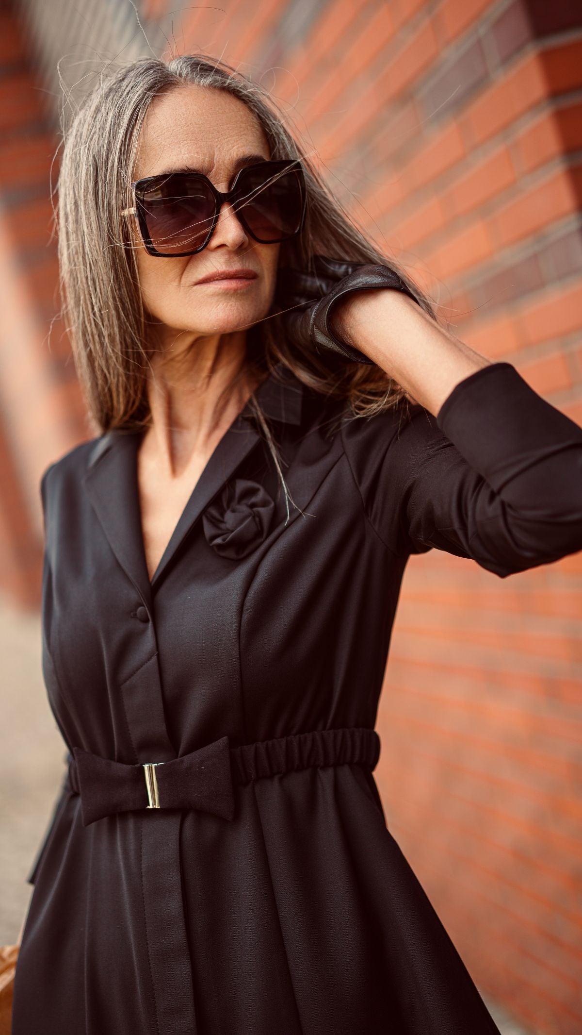 Modelka w czarnej wełnianej sukience uśmiecha się. Zbliżenie