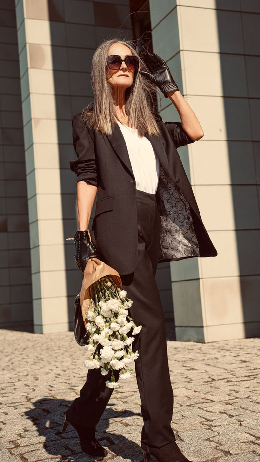 Modelka w czarnej marynarce i czarnym spodniach garnituorwych cygaretkach idzie z pracy ZAQANNA