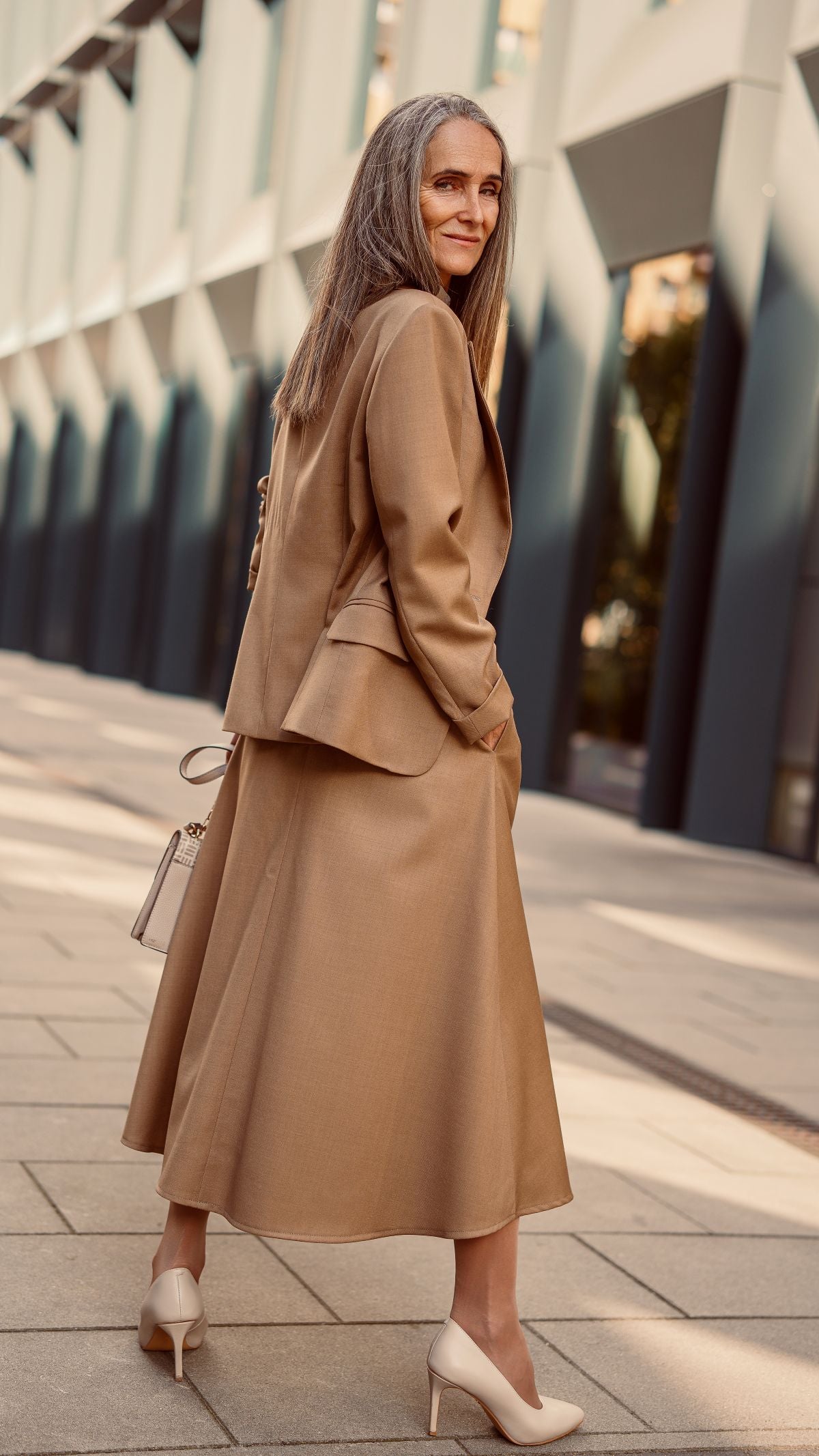 Modelka w wełnianym garniturze stoi obrócona tyłem